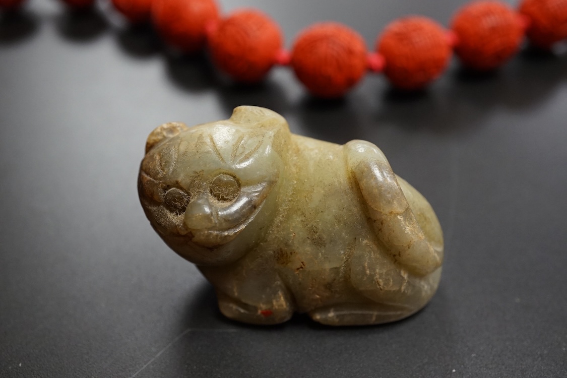 A Chinese red lacquered bead necklace and a bowenite jade figure of a cat